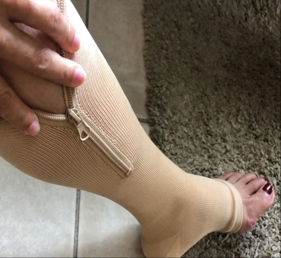 Person wearing a beige compression stocking on a carpeted floor.